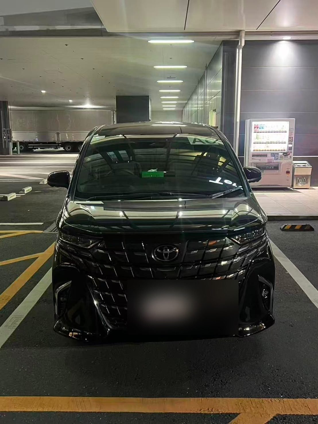Toyota Alphard waiting at a terminal pickup area at night