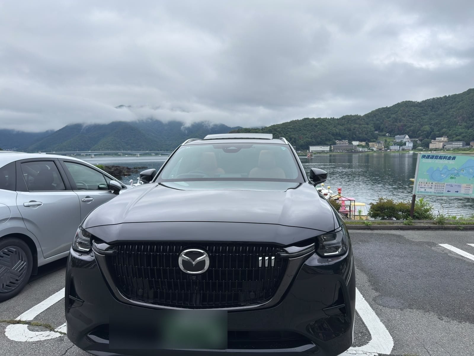 SUV parked in front of Lake Kawaguchi with mountains behind